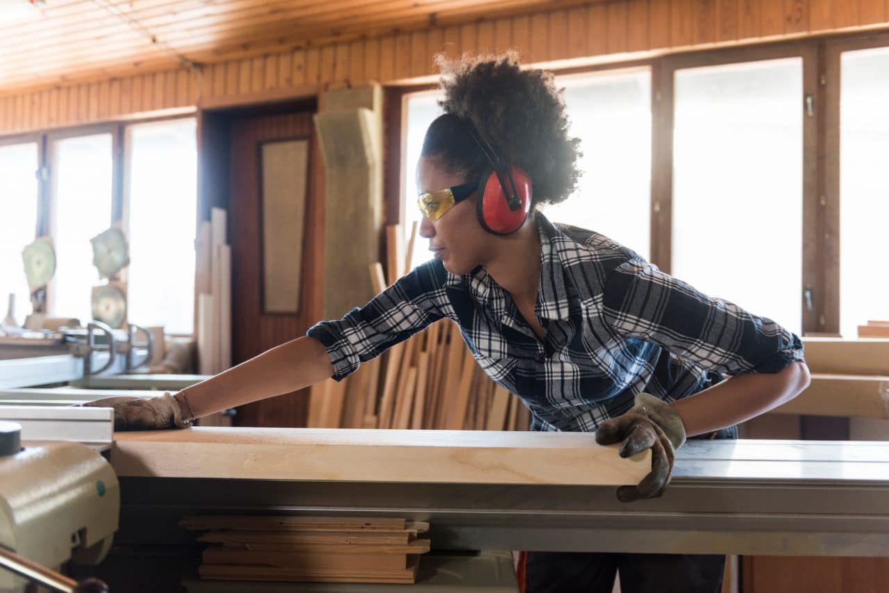 Person woodworking with power tools and wearing protective glasses and headphones