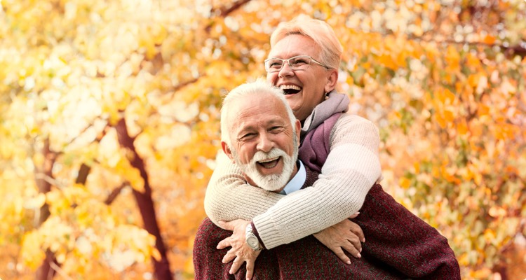 A couple laughing together under a tree in fall
