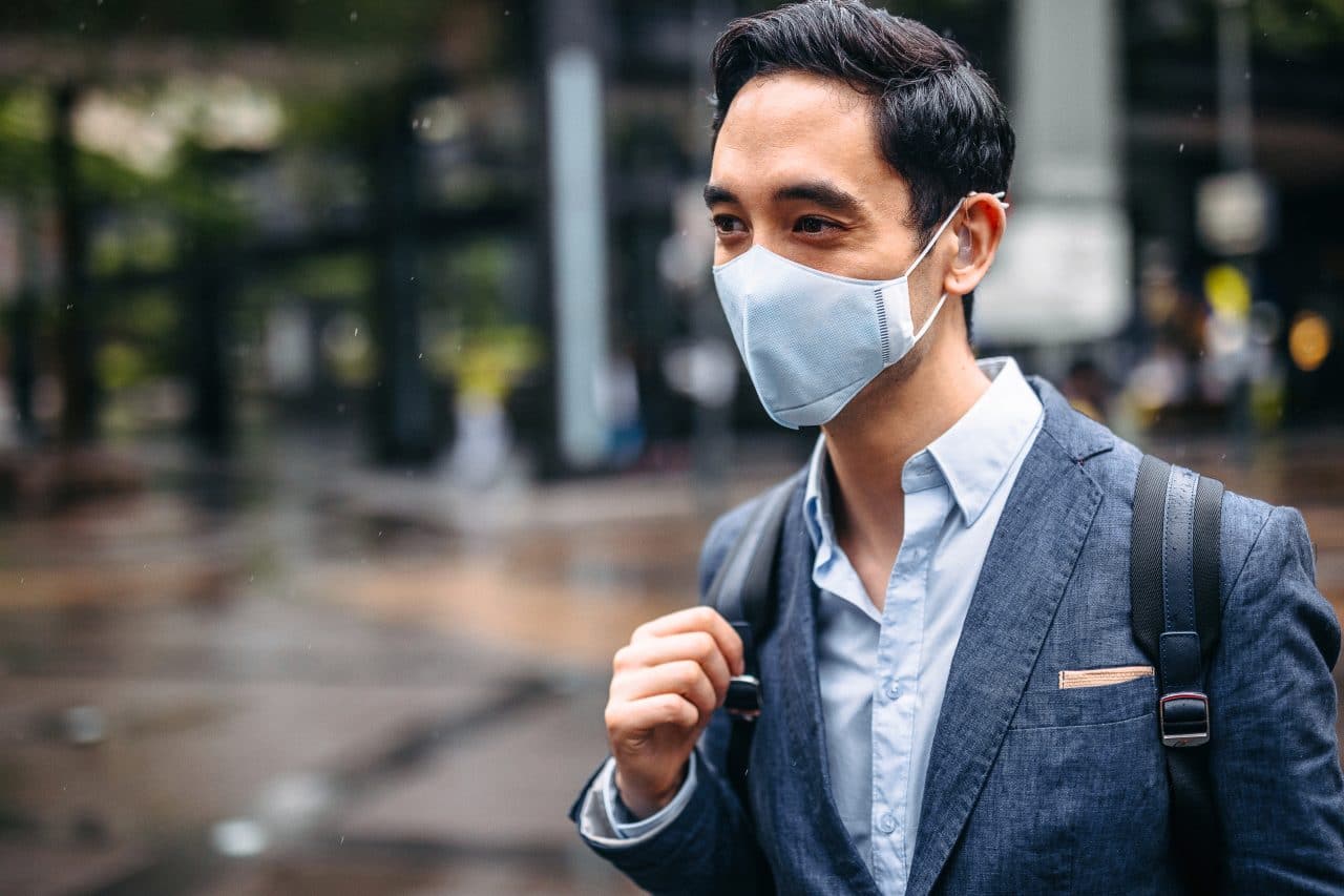 Businessman wearing pollution mask in city