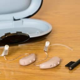 Close up of a pair of hearing aids on bedside table.