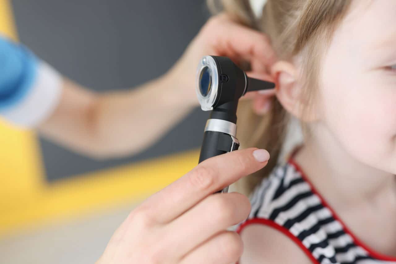 Doctor examines the ear of a young girl.