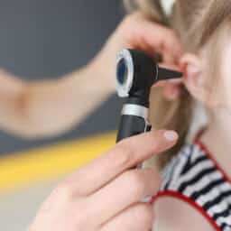 Doctor examines the ear of a young girl.