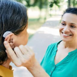 Woman with hearing aid talking to her friend outside.