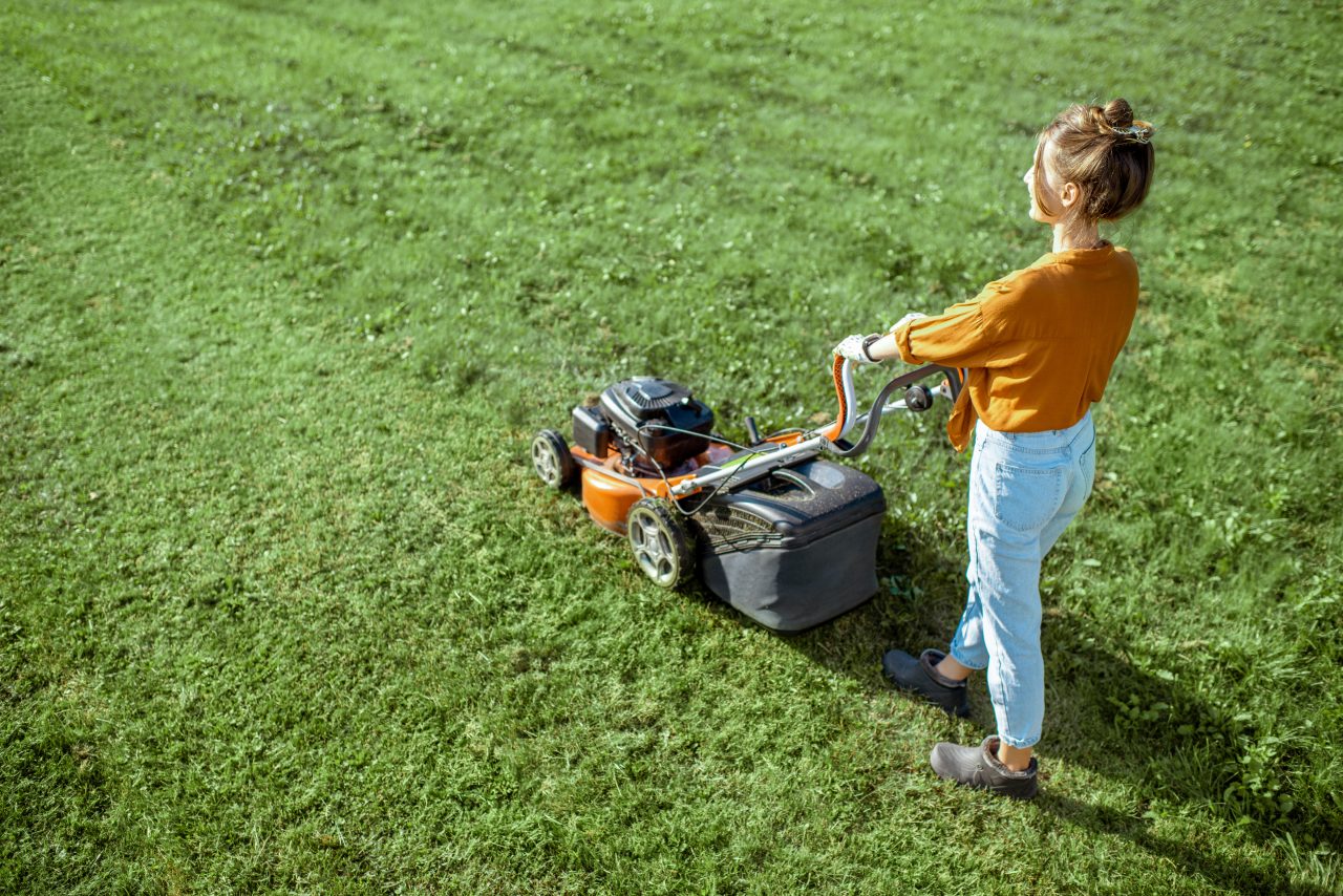 a woman mows her lawn