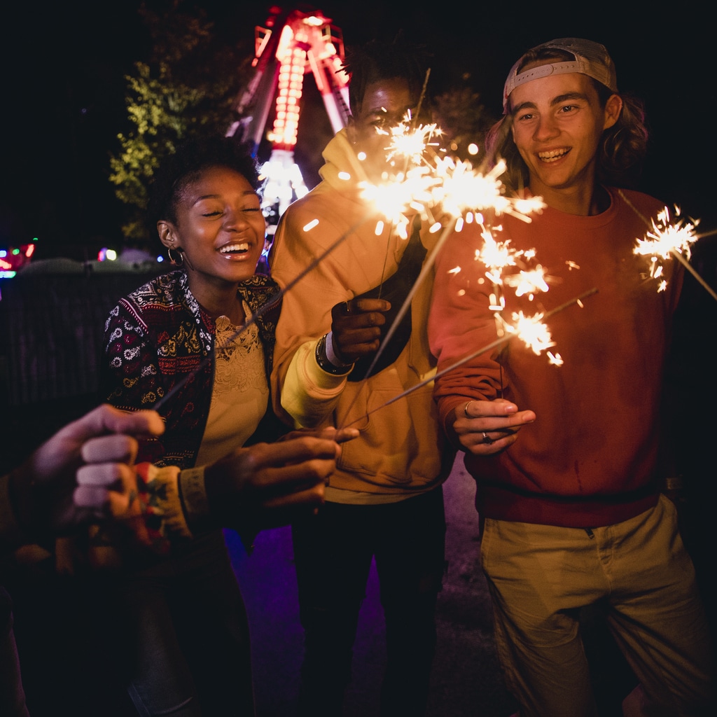 Group of friends lighting sparklers on the fourth of July.