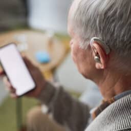 Man with hearing aids looks at phone