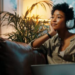 Woman sitting on the couch listening to music through headphones