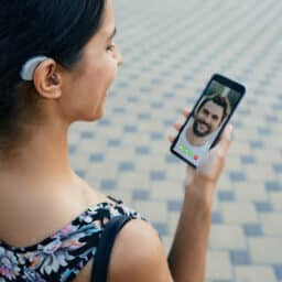 woman with a hearing aid behind the ear communicates with her boyfriend via video call